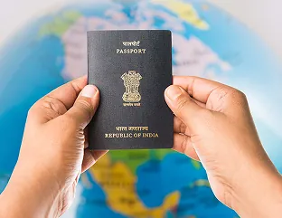 Hands holding an Indian passport in front of a globe