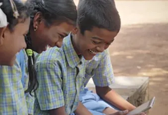 Students from a rural school smiling at a tablet