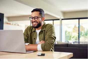 A working professional smiling at a laptop